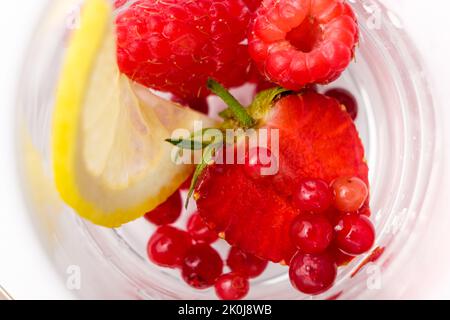 Cocktail estivo rinfrescante con fragole, frutti di bosco, limone e ghiaccio, vista dall'alto. Foto Stock