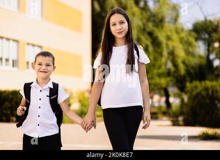 La sorella maggiore si prende cura del fratello minore, tiene la mano e va a scuola. Foto Stock