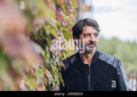 Ritratto di un uomo di mezza età che si appoggia contro una parete del superriduttore mentre si guarda via Foto Stock