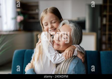 Piccola nipote soddisfatta e nonna anziana europea abbracciando, divertirsi insieme godere tenero momento Foto Stock