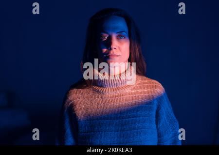 Primo piano di una donna solitaria che soffre di insonnia e depressione, seduta da sola in una stanza buia. Foto Stock