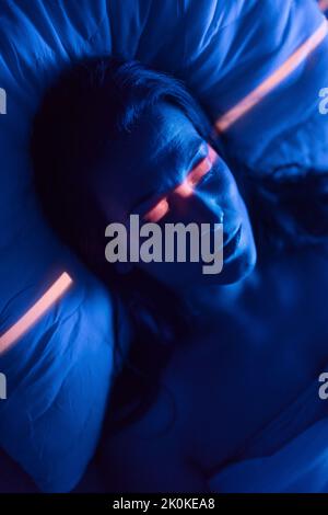 Primo piano di una donna solitaria che soffre di insonnia e depressione, sdraiata a letto di notte. Foto Stock