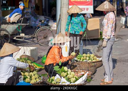 Venditore vietnamita che indossa cappello di bambù che lavora nel mercato di strada all'aperto, Hai Phong, Vietnam Foto Stock