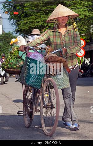 Venditore vietnamita che indossa cappello di bambù che lavora nel mercato di strada all'aperto, Hai Phong, Vietnam Foto Stock