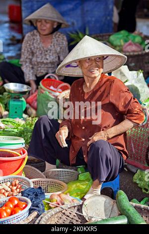 Venditore vietnamita che indossa cappello di bambù che lavora nel mercato di strada all'aperto, Hai Phong, Vietnam Foto Stock