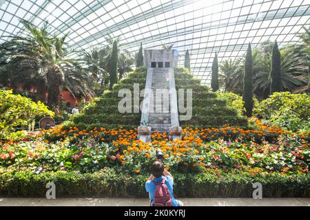 Un giovane ragazzo che scatta foto della riproduzione alta 4,5 m dell'iconica piramide di Chichén Itzá dei Maya. Gardens by the Bay, Singapore. Foto Stock