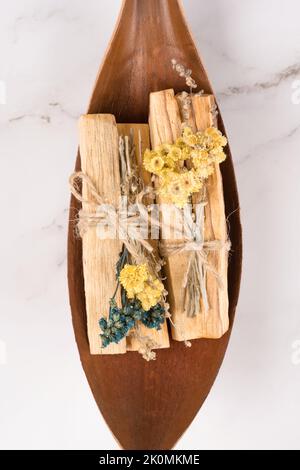 Sbavatura di bastoncini di pala santo decorati con erbe aromatiche secche. Rituale di fumigazione per yoga e meditazione. Composizione verticale Foto Stock