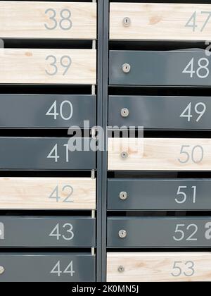 Anche righe di caselle postali numerate. Cassette postali in metallo vicino all'entrata in un moderno edificio di appartamenti. Foto verticale Foto Stock