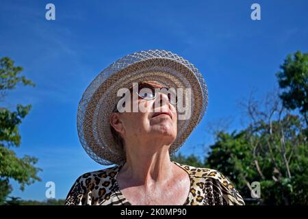 Donna anziana che prende il sole nel parco Foto Stock