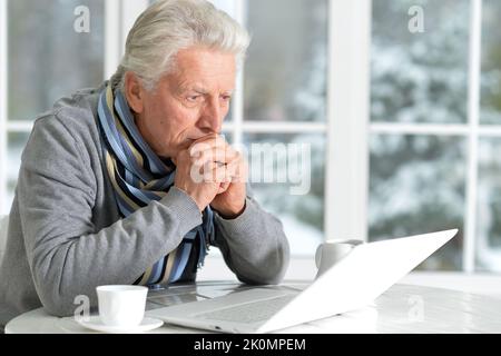 L'uomo anziano siede sullo sfondo della finestra in inverno Foto Stock