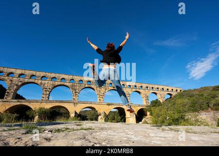 Vista della donna che salta di fronte a Pont du Gard, Francia, Europa Foto Stock