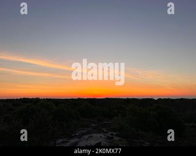 Una vista aerea dell'alba arancione sulla silhouette di lussureggianti boschi verdi Foto Stock