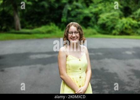 Tween ragazza quasi adolescente con bretelle e indossare una sundress giallo all'esterno in estate Foto Stock