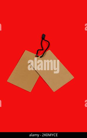 Etichetta di cartone marrone vuota con stringa su sfondo rosso. Cartellino testurizzato vintage. Etichetta di cartone mockup. Prezzo tag, gift tag, vendita tag, indirizzo la Foto Stock