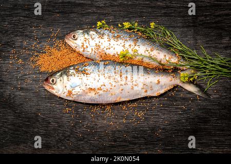 Hilsa cruda cruda o terubok con senape e foglie verdi su tavola nera. Un piatto bengalese popolare. Pesce nazionale del Bangladesh. Padma ilish anche famo Foto Stock