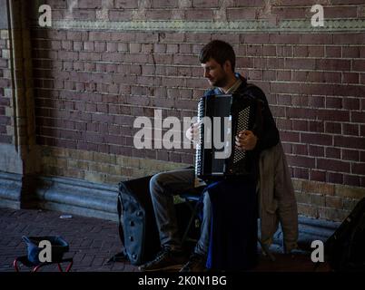 Musicista di strada che suona la fisarmonica in un sottopassaggio di Amsterdam Foto Stock