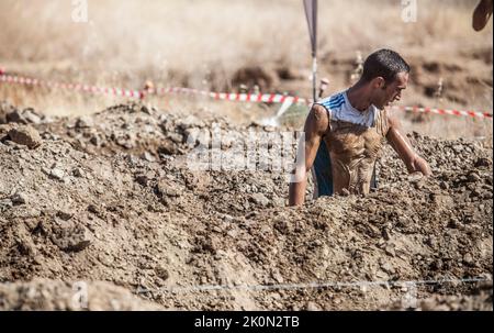 Merida, Spagna - 11th settembre 2022: FarinatoRace Merida 2022. Percorso di ostacoli più difficile al mondo. Trincea allagata con filo spinato Foto Stock