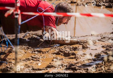 Merida, Spagna - 11th settembre 2022: FarinatoRace Merida 2022. Percorso di ostacoli più difficile al mondo. Strisciamento sotto il filo Foto Stock