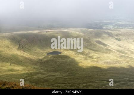 Llyn CWM Llwch lago glaciale nella nuvola sotto Pen y Fan, Brecon Beacons, Powys, Wales, UK Foto Stock