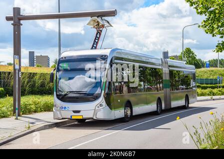 Autobus cittadino elettrico presso una stazione di ricarica in una giornata di sole estate Foto Stock