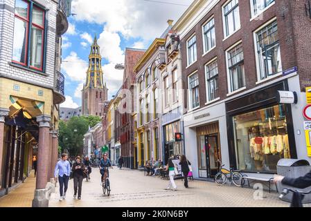 Groningen, Paesi Bassi - 20 giugno 2022: Persone che camminano e pedalano lungo Brugstraat costeggiata da edifici storici nel centro storico della città Foto Stock