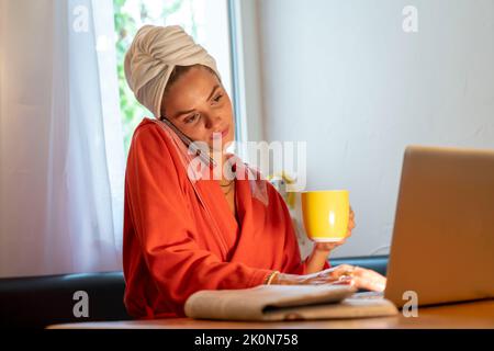 Immagine simbolica Precrastinazione, giovane donna cerca di fare molte cose allo stesso tempo, dopo il bagno, sul computer, telefono, giornale, e colazione Foto Stock