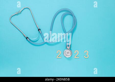 Stetoscopio medico e i numeri nuovo anno 2023 su sfondo blu. Natale e Capodanno concetto. Creative medico sfondo invernale, cartolina Foto Stock