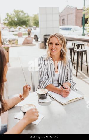 Due donne che hanno una riunione di lavoro all'esterno della caffetteria Foto Stock