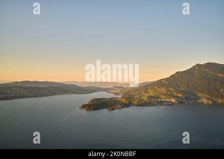 Mare con montagne sotto il cielo del tramonto Foto Stock