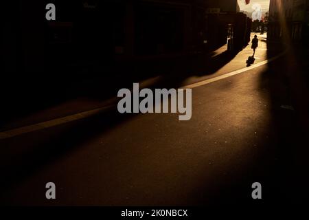 Anonimo donna che cammina sulla strada in luce del sole Foto Stock