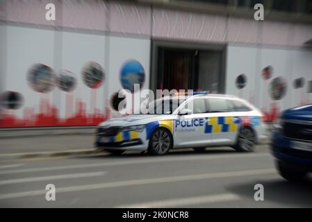 Una macchina di polizia con luci lampeggianti e sirena piangendo teste di un'emergenza a Christchurch, la città di Quake della Nuova Zelanda. Immagine distorta con radiale Foto Stock