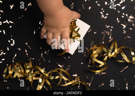 Scatola regalo apribile a mano per bambini su fondo nero con cordonella d'oro su tavolo nero . Composizione per natale, Capodanno , compleanno, festa della mamma, venerdì nero , vendita, promozioni, natale o matrimonio. Foto Stock