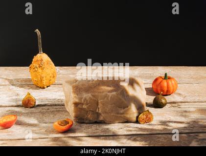 Composizione in stile retrò fatta di zucca, zucca, albicocche e roccia su vecchio tavolo di legno. Podio del prodotto, adatto per l'esposizione del prodotto. Sfondo scuro. Foto Stock