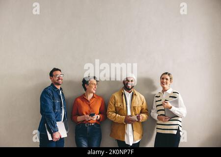 Allegro businesspeople sorridente felice mentre aspetta in fila per un'intervista. Gruppo di candidati selezionati che detengono dispositivi digitali diversi Foto Stock