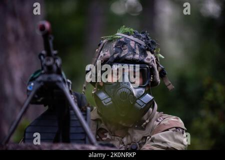 Un paracadutista dell'esercito degli Stati Uniti assegnato a 4th battaglione, 319th Airborne Field Artillery Regiment fornisce la sicurezza perimetrale con un attacco M249 durante un attacco chimico, biologico, radiologico e nucleare (CBRN) al Joint multinazionale Readiness Center di Hohenfels, Germania come parte dell'Exercise Saber Junction 22, 12 settembre 2022. Saber Junction 22 è un esercizio di rotazione multinazionale progettato per valutare la disponibilità della Brigata aerea 173rd dell'esercito statunitense ad eseguire operazioni terrestri unificate in un ambiente congiunto e combinato e per promuovere l'interoperabilità con più di 4.500 partecipanti del Foto Stock