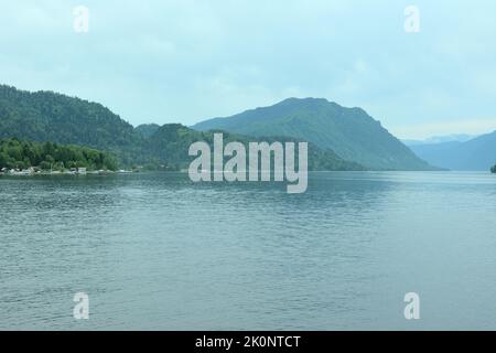 Un frammento di un bel lago nella nebbia mattutina lungo le rive, circondato da pendii di montagna ricoperti di foresta di conifere. Lago Teletskoye, al Foto Stock