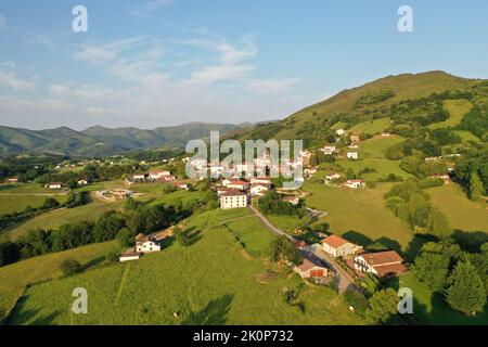 Vista aerea del villaggio di Zugarramurdi nelle verdi colline di Navarra, che mostra l'architettura rurale, i paesaggi lussureggianti e una tranquilla valle di montagna. Foto Stock