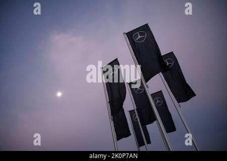 Stoccarda, Germania. 13th Set, 2022. La stella Mercedes può essere vista sulle bandiere vicino allo stabilimento di Untertürkheim del costruttore di automobili Mercedes-Benz, con la luna che splende sullo sfondo. La Corte Regionale di Stoccarda sta per annunciare una decisione sulla causa climatica intentata da Deutsche Umwelthilfe (DUH) contro Mercedes-Benz. Credit: Marijan Murat/dpa/Alamy Live News Foto Stock