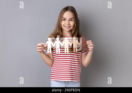 Ritratto di bambina che indossa T-shirt a righe con catena di carta multirazziale persone, comunità, unità, persone e concetto di supporto. Studio in interni isolato su sfondo grigio. Foto Stock