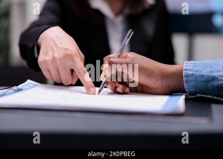 Il paziente compila i documenti di report alla reception, firmando i moduli di registrazione prima di partecipare all'appuntamento per la visita di controllo. Donna che scrive i file di controllo con l'addetto alla reception, assistenza sanitaria. Primo piano. Foto Stock