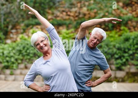 Anziani che rimangono attivi. Una coppia anziana che fa yoga insieme all'aperto. Foto Stock