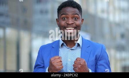 L'uomo d'affari afroamericano guarda con espressione felice Foto Stock