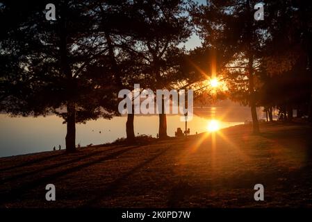 Riflesso del sole sulla superficie dell'acqua. Ora d'oro e tramonto sul lago. Foto Stock