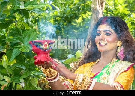 Donne sposate che eseguono dhunuchi danza in occasione di Durga Agomoni come rituale, il fumo Santo copriva tutta la zona. Foto Stock