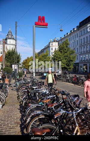 Segnale della metropolitana, stazione Nørreport, biciclette parcheggiate in primo piano; Frederiksborggade Copenaghen, Danimarca Foto Stock