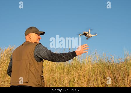 Nida, Lituania - 9.12.2022: Maschio cattura sbarco Drone Dji mavic mini. Foto Stock