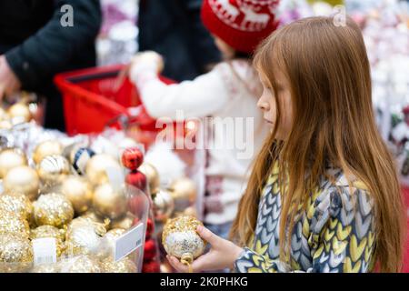 Un ragazzo carino sceglie i giocattoli dell'albero di Natale in un centro commerciale. Foto di alta qualità . Concetto di Natale e Capodanno. I bambini scelgono i regali per Natale. Sconti del Black Friday. Foto Stock