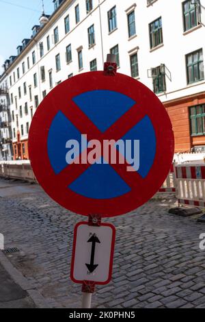 Sulla strada non ci sono fermate o cartelli per il parcheggio, con un edificio bianco e arancione sullo sfondo Foto Stock