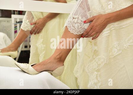 Sposa indossa le scarpe il giorno del suo matrimonio. Concetto di prepararsi al mattino per il giorno del matrimonio. Foto Stock