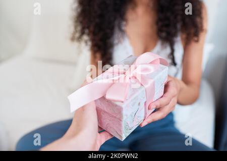 Primo piano della mano dando grazioso regalo avvolto in fiocco rosa nel letto Foto Stock